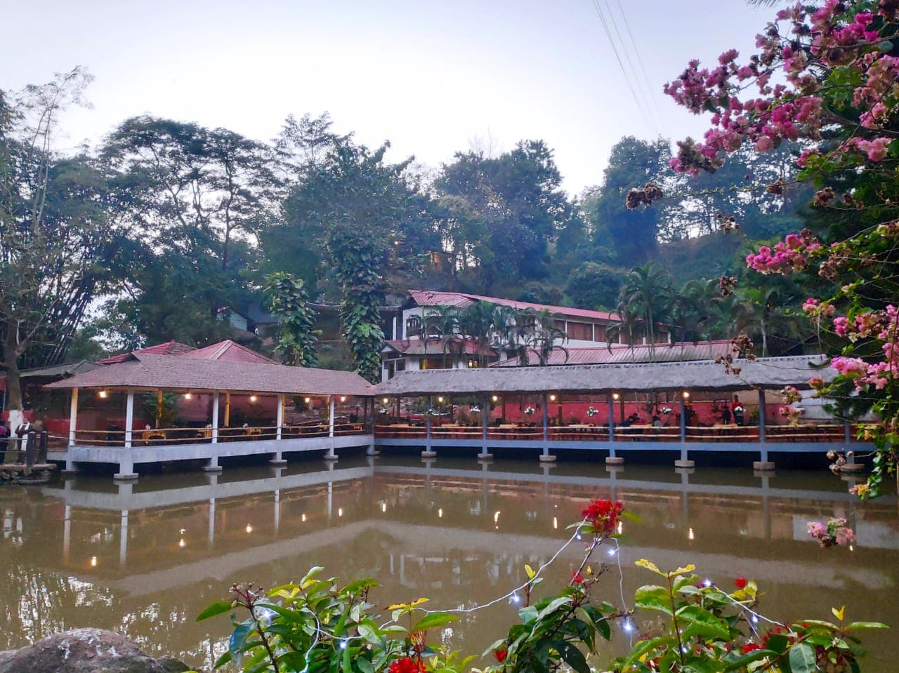 The resort seen across the pond, flowering shrubs in the foreground